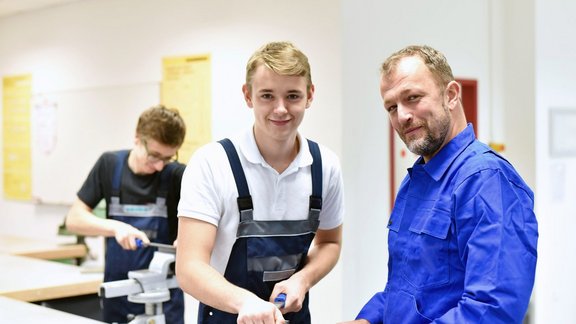 Lehrer mit Schüler. Der Schüler lernt handwerkliches Arbeiten. 